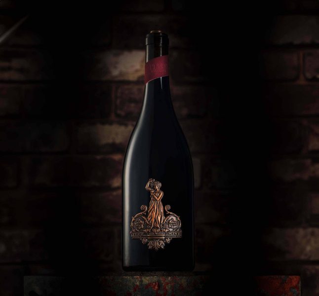 Full bottle image featuring the sculpted die-cast metal badge by Signet